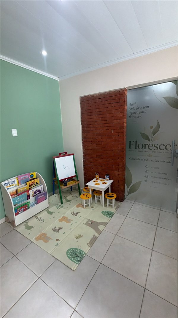 Cantinho infantil com livros, quadro para desenhar e mesa com banquinhos