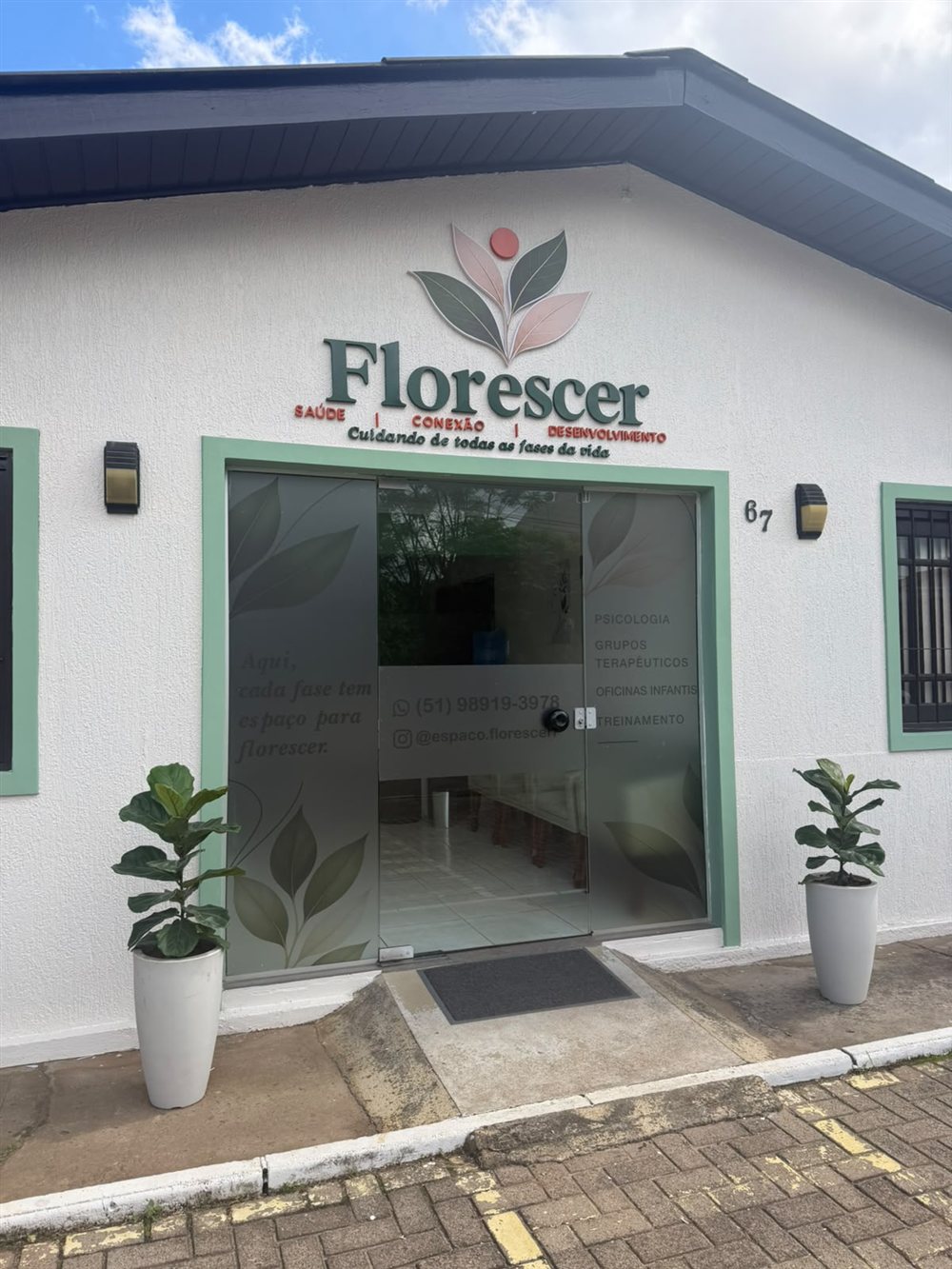 Fachada do Espaço Florescer, com identificação acima da porta e número 67 ao lado da entrada