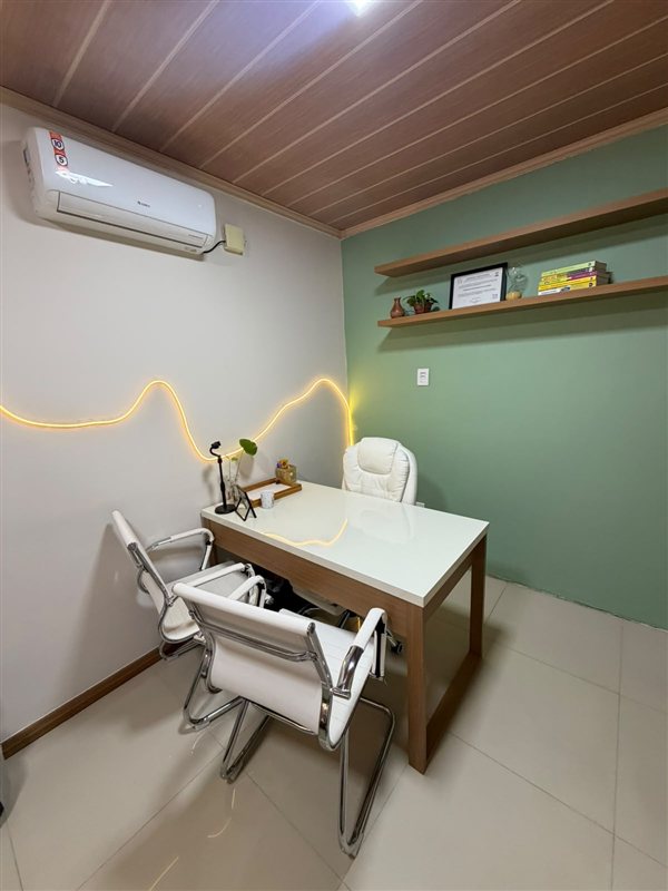 Sala de atendimento com mesa branca, cadeiras e parede verde