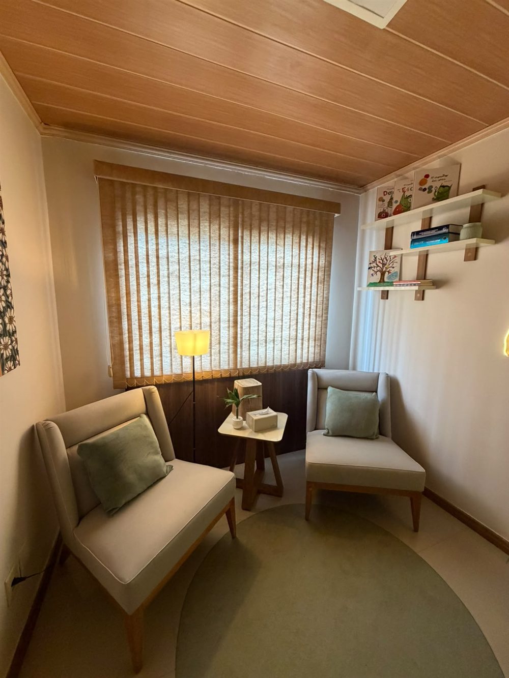 Sala do Espaço Florescer com duas poltronas, almofadas verdes e iluminação suave