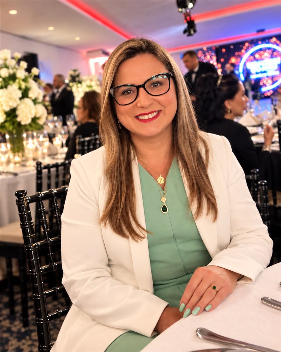 Retrato de Silvene Almeida, sorrindo, com blazer branco e blusa verde